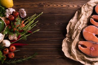 Fresh raw salmon fish steak with herbs and vegetables on wooden background