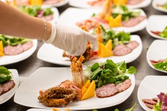 Many plates of appetizer being prepared in restaurant kitchen